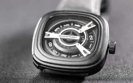 Square shaped used wrist watch on a slightly textured surface under studio lights macro photoの写真素材