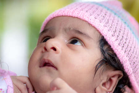 Cute baby with pink crochet hat looking at mothers. One-month-old daughters first photo session celebrating one month's birthday.のeditorial素材