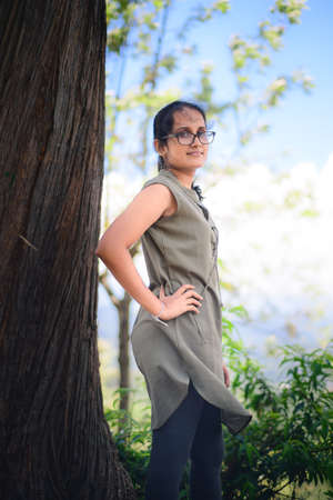 Beautiful girl posing for a photo hands in the hips and turns sideways against the misty mountain background wearing spectacles.のeditorial素材