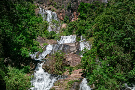Beautiful Rawana Ella waterfall, surrounded by green tropical forest.