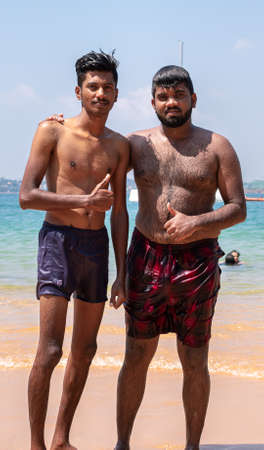 Galle, Sri Lanka - 01 31 2020: Brothers at the beach, giving thumbs up hand signal and posing in front of the jungle beach sea as the background close up portraiture photograph,のeditorial素材
