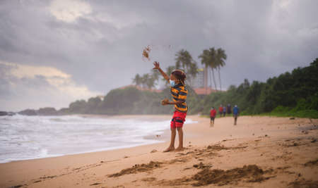 Small kid Throwing sand balls at the sea. Concept of freedom and playfulness of childhood.の写真素材