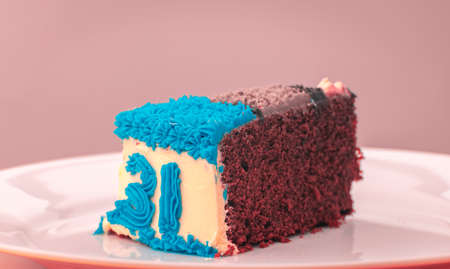 31st birthday party celebration, Chocolate icing cake slice on a plate, number 31 in blue icing decoration on the side. Delicious beautiful mouthwatering cake slice close up.の写真素材