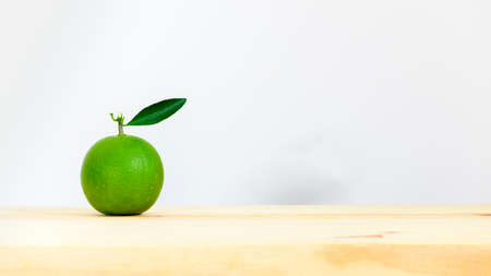 Raw sweet orange fruit on a wooden board against the white background side view, orange with the green leaf isolated.の写真素材