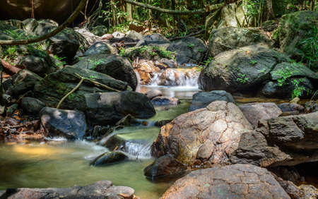 Clean and pure water streams in the creek flow through the rock boulders, Beraliya tropical...