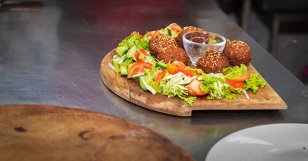 Falafel plate with vegetables salad and sauce on the kitchen table close up.