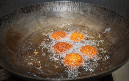 Deep frying falafel balls in a wok, hot cooking oils bubbling, and falafel balls turned golden brown color.の写真素材