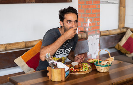 Weligama, Sri Lanka -10 12 2022: A man eating a falafel dish on a restaurant tableのeditorial素材