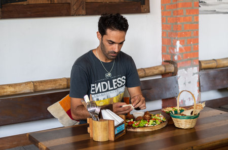 Weligama, Sri Lanka -10 12 2022: A man eating a falafel dish on a restaurant tableのeditorial素材