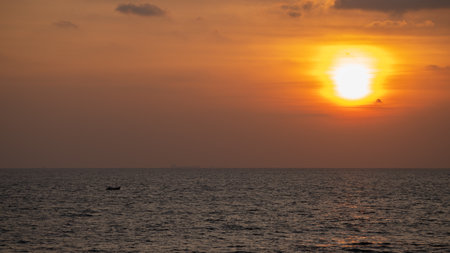 Sunset on the horizon, a small fishing boat traveling alone.の写真素材
