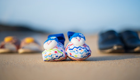 Concept of expectant parents, baby shoes and parent's shoes on the beach sand.の写真素材