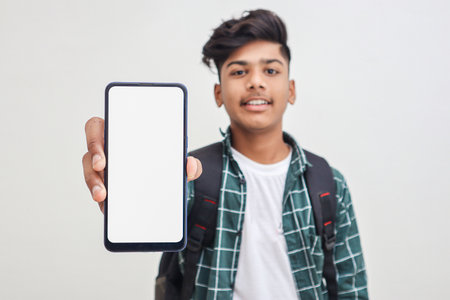 Young indian college student showing smartphone Screen on white background.の写真素材