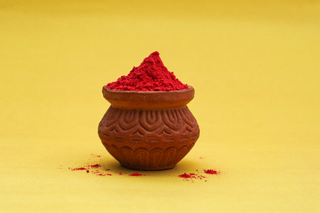 Indian festival Holi concept Red colour bowl on yellow background.の写真素材