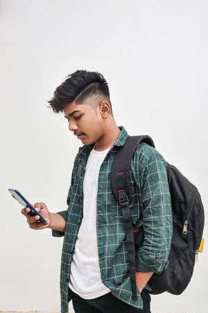Indian college student using smartphone on white background.