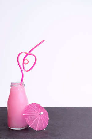 Glass jar with a strawberry smoothie and a straw in the shape of a heartの写真素材
