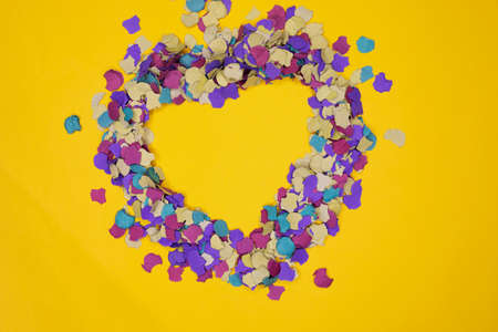 Heart silhouette made with confetti on yellow backgroundの写真素材