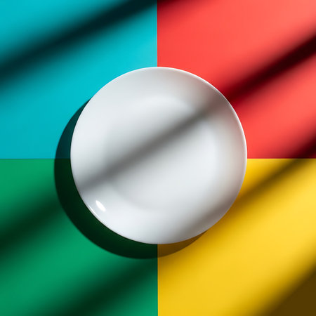 A clean white plate sits centrally on a colorful background divided into four distinct vibrant quadrants.の素材