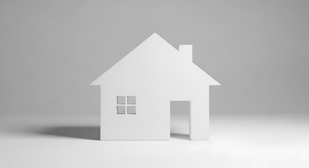 A stark white, simplified house shape stands against a neutral gray background, casting a subtle shadow.の素材