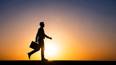 A confident businessman walks towards a vibrant sunset, briefcase in hand, exuding determination and ambition.の素材