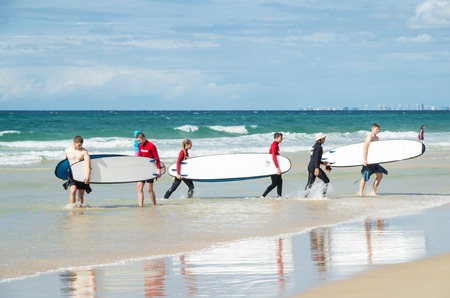 Gold Coast, Australia - July 11, 2017: young surfers carrying their surfboards across the beach at Surfers Paradise.のeditorial素材