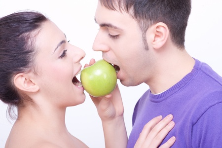 young couple with a green apple between their lipsの写真素材