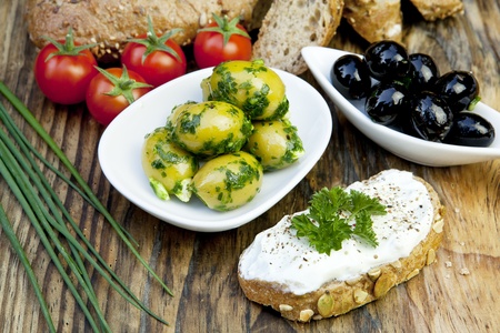 green olives with fresh bread and herbs on wooden backgroundの写真素材