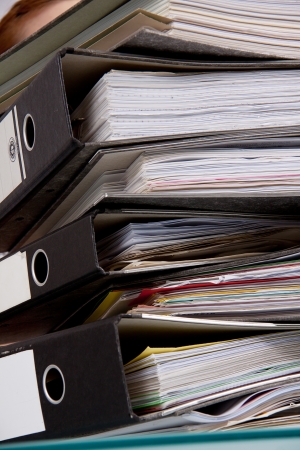business woman in office looks at unbelievable folder stack isolated on whiteの写真素材