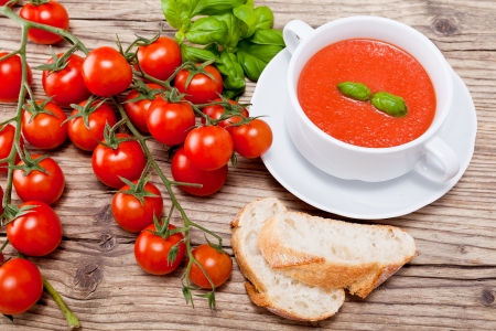 tasty fresh tomato soup basil and bread on wooden backgroundの写真素材