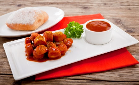 curry wurst spicy sausage with curry and ketchup on wooden backgroundの写真素材