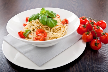 fresh tasty pasta spaghetti with tomatoes parmesan and basil on tableの写真素材