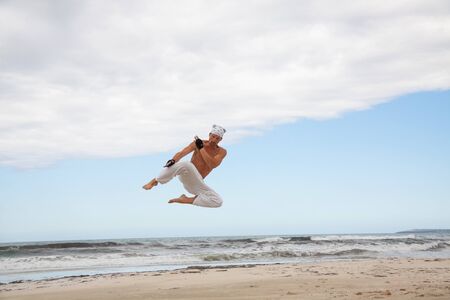 man is jumping sport karate martial arts fight kick jump beach summertime