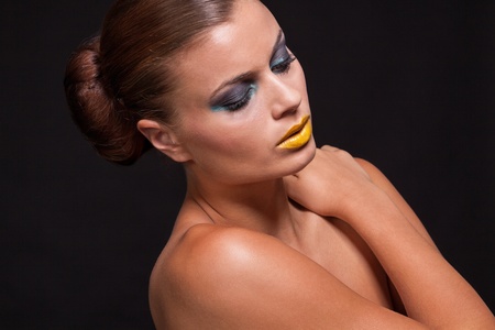 woman with extreme colorfull make up in blue and yellow on black background
