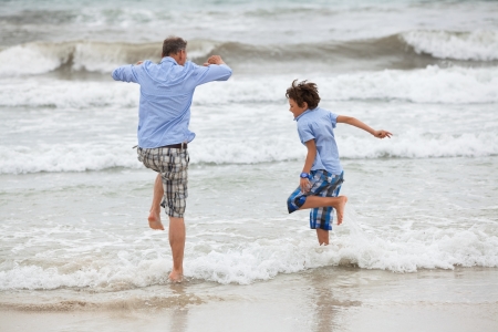 father and sons on the beach playing in the sand holiday family の写真素材