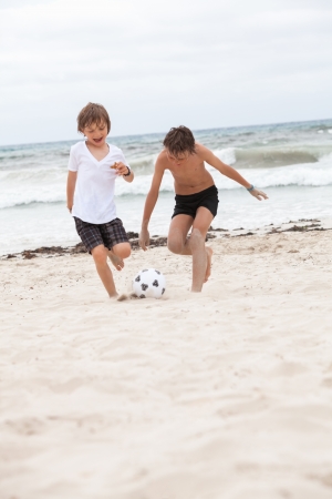 happy family father two kids playing football on beach summer fun soccerの写真素材