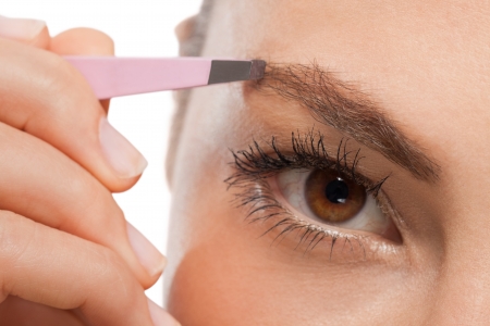 youtg beautiful woman eyebrow plucking tweezers eyes hair  closeup portraitの写真素材