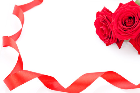 Bouquet of beautiful fresh red roses with a coiled ribbon border isolated on white with plenty of copyspace for your loving anniversary or Valentines messageの写真素材