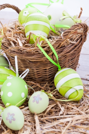 Collection of four hand decorated colourful green Easter eggs with different patterns displayed in straw, close up viewの写真素材