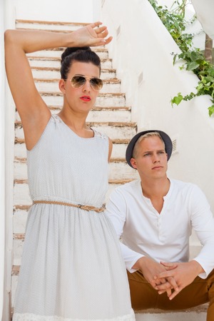 Elegant trendy young couple in fashionable modern clothes and accessories posing outdoors in the summer sunshine in a garden or parkの写真素材