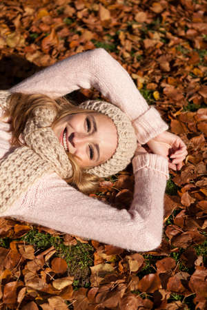 young smiling woman with hat and scarf outdoor in autumn nature backgroundの写真素材
