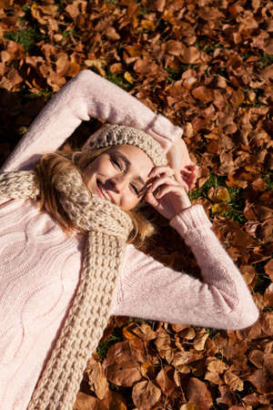 young smiling woman with hat and scarf outdoor in autumn nature backgroundの写真素材