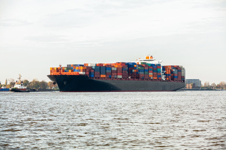 Fully laden container ship in port with its decks stacked with metal containers full of freight and...