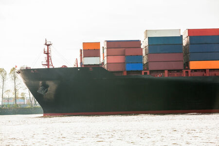 Fully laden container ship in port with its decks stacked with metal containers full of freight and...