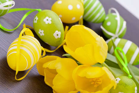 Colourful yellow and green hand painted Easter Eggs with traditional patterns nestling amongst the...