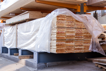 Wooden panels stored inside an industrial warehouse on metal shelving for use in construction and building, nobody in viewの写真素材