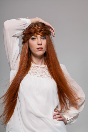 Pretty female model with serious look posing with hand on waist on white backgroundの写真素材