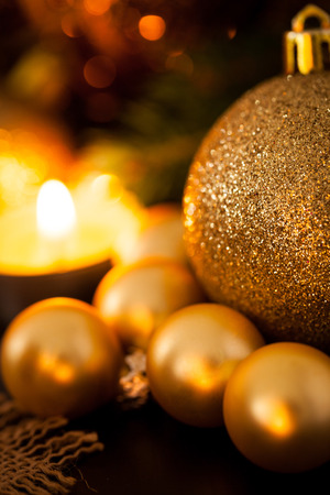 Warm gold and red Christmas candlelight background with burning tea lights amongst random gold and red baubles in a warm glowing light with copyspaceの写真素材