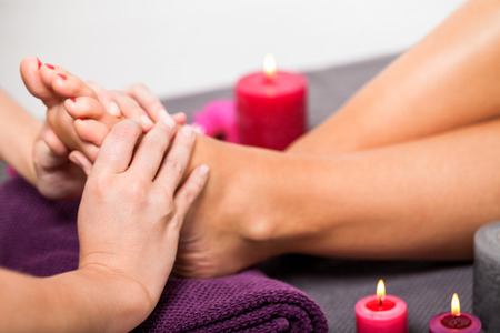 Woman having a pedicure treatment at a spa or beauty salon with the pedicurist massaging the soles of her feet with a pumice stone to cleanse dead skin and stimulate the tissueの写真素材