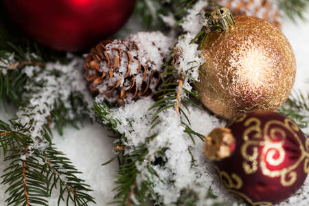 Several assorted Christmas ornaments in snow covered treeの写真素材