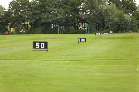 Two Empty Golf Ball Baskets at Driving Range with Hole and Flag in Backgroundの写真素材