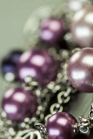 Close up of three attractive shiny purple beads attached by silver chains on an item of jewellery in a fashion and handicraft conceptの写真素材